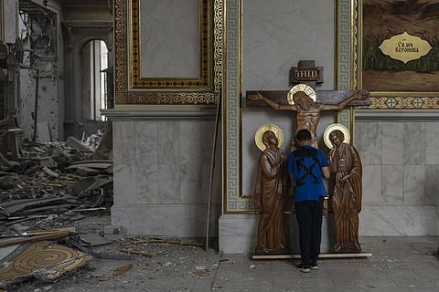 A boy kisses the statue of Jesus while helping clean up inside the Odesa Transfiguration Cathedral after the church was heavily damaged in Russian missile attacks (Photo | AP)