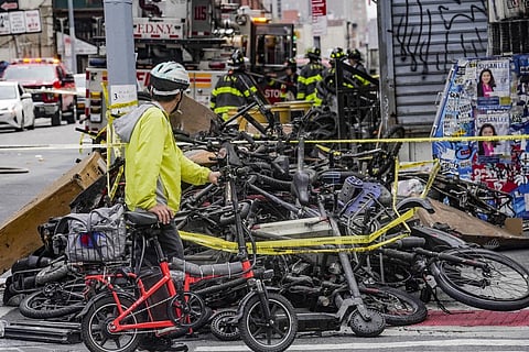 A biker stops to look at a pile of e-bikes in the aftermath of a fire in New York, which authorities say started at an e-bike shop and spread to upper-floor apartments on June 20 (Photo | AP)
