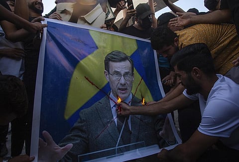 Iraqis burn the picture of Sweden's prime Ulf Kristersson during a protest in Tahrir Square in Baghdad (Photo | AP)