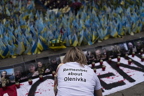 A woman places candles at a memorial in Kyiv to mark the first-year anniversary of the attack on a prison building in Olenivka, eastern Ukraine. (Photo | AP)