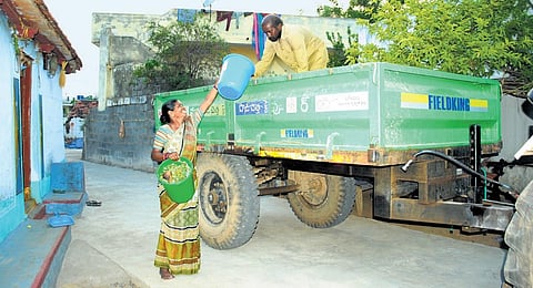 A resident hands over two buckets of garbage