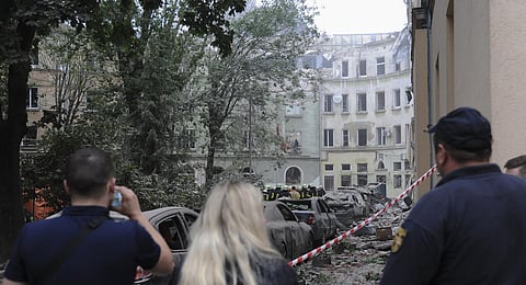 People watch as emergency service workers continue to search for victims after a Russian missile attack in Lviv, Ukraine. (Photo | AP)