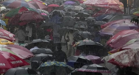FILE - People walk holding umbrellas past street vendors under beach umbrellas at a market during rain in Mumbai, Tuesday, July 18, 2023. (Photo | AP)