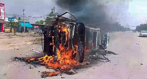 A vehicle set on fire by miscreants after clashes broke out during a religious procession, in Nuh. (Photo | PTI)