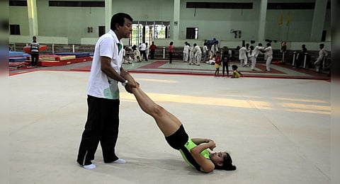 FILE - Indian gymnast Dipa Karmakar (R) stretches with her coach Bisbeshwar Nandi during a practice session in Agartala. (Photo | AFP)