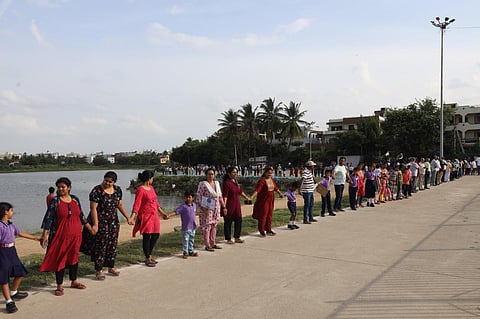 School children and member of various NGOs form a human chain at Kapra Lake in Sainikpuri on Sunday. (Photo | Sri Loganathan Velmurugan)