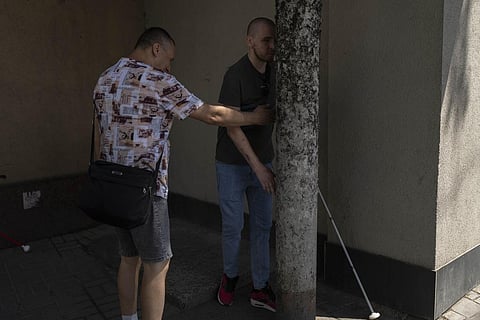 A trainer holds out his arm to prevent Ivan Soroka, a former Ukrainian soldier blinded in the war, from colliding with a pole on the streets of Rivne, Ukraine, Friday, July 21, 2023. (Photo | AP)