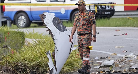 A member of the fire and rescue department inspect the crash site of a small plane in Shah Alam district, Malaysia, Thursday, Aug. 17, 2023. (Photo | AP)