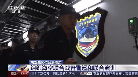 In this image taken from video footage run by China's CCTV, Chinese sailors run past a insignia with the words 'Chinese Navy Nantong Vessel'. (Photo | AP)