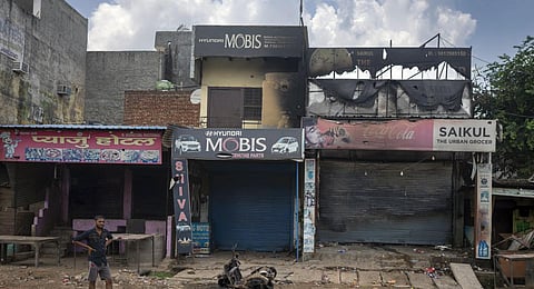 A man stands next to partially burnt shops in Sohna near Nuh in Haryana state, India, Tuesday, Aug., 1, 2023. Deadly clashes between Hindus and Muslims began in the area Monday afternoon.(Photo | AP)