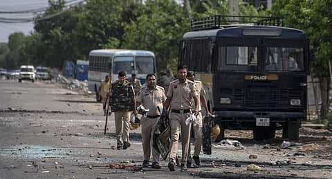 Broken glass and debris are strewn on a street as policemen patrol after communal clashes in Nuh, Haryana, Tuesday, Aug 1, 2023. (Photo | AP)