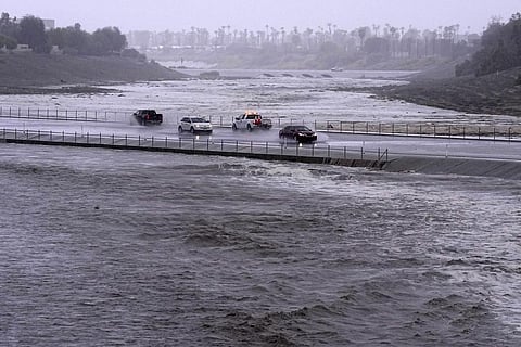 Vehicles cross over a flood control basin that has almost reached the street, Sunday, Aug. 20, 2023, in Palm Desert, Calif. (Photo | AP)