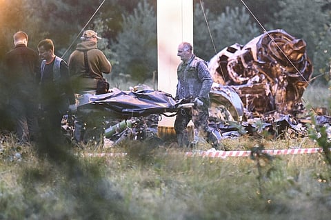 People carry a body bag away from the wreckage of a crashed private jet, near the village of Kuzhenkino, Tver region, Russia, Thursday, Aug. 24, 2023. (Photo | AP)
