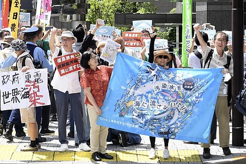 Protester holds a sign during a rally against the treated radioactive water release from the damaged Fukushima nuclear power plant. (Photo | AP)