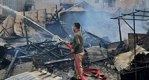A firefighter douses flames after unidentified miscreants burnt three houses, in Imphal, Sunday, Aug. 27, 2023. (Photo | PTI)