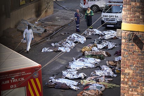 Medics stand by the covered bodies of victims of a deadly blaze in downtown Johannesburg, Thursday, Aug. 31, 2023. (Photo | AP)