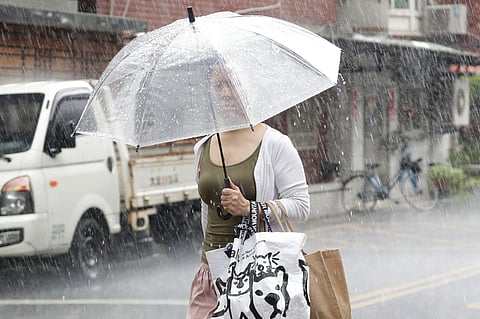 A woman holds an umbrella in heavy rain after Typhoon Saola moves away in Taipei, Taiwan. (Photo | AP)