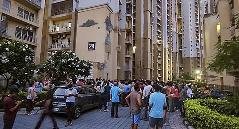 Locals gather near the area where a 73-year-old woman died of possible cardiac arrest after the cable of a lift at a housing complex snapped, leading to a free fall.(Photo | PTI)