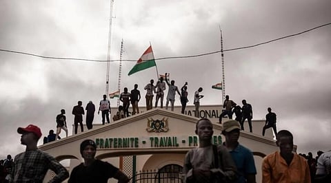 Protesters hold a Niger flag during a demonstration on independence day in Niamey. (Photo | AFP)