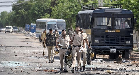 Broken glass and debris are strewn on a street as policemen patrol after communal clashes in Nuh in Haryana state, India, Tuesday, Aug., 1, 2023.(Photo | PTI)
