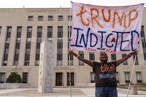 A protestor holds a banner outside federal court in Washington after Donald Trump was charged by the US Justice Department for trying to overturn the 2020 presidential election. (Photo | AP)