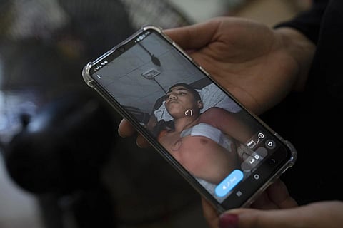 Palestinian mother Ashwaq Abu al-Wafa shows a photo of her 14-year-old son Ammar Abu al-Wafa under medical treatment after suffering a bullet injury during an Isreali army operation. (Photo | AP)
