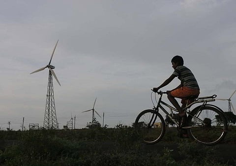 Boy riding a bicycle against the backdrop of a windmill in the outskirts of Coimbatore. (Photo | S Senbagapandiyan)