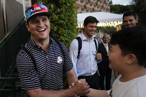 USA Ryder Cup team captain Zach Johnson shakes hands with a fan as he returns with members of his team at a hotel in Rome. (Photo | AP)