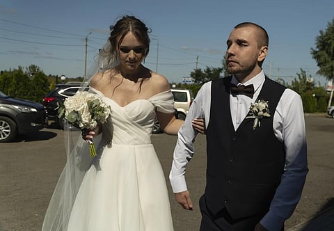 Bride Vladislava Ryabets, left, helps groom Ivan Soroka, right, to walk during their wedding day in Kyiv, Ukraine, Sept 9, 2023. (Photo | AP)