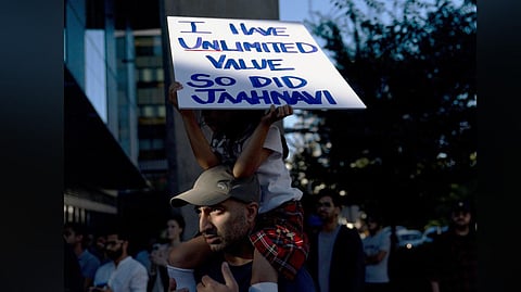 A girl sits atop her father's shoulders while holding a sign for Jaahnavi Kandula, during a protest in Seattle, after the footage of a cop joking about her death came to light.