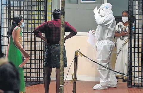 A healthcare professional in PPE kit interacts with bystanders of patients admitted to the Kozhikode Medical College Hospital with Nipah symptoms | E Gokul