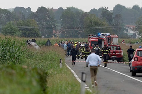 The debris of a burnt car is seen on the left as firefighters seal off the area where an aircraft of the Italian acrobatic air team the Frecce Tricolori crashed. (Photo | AP)
