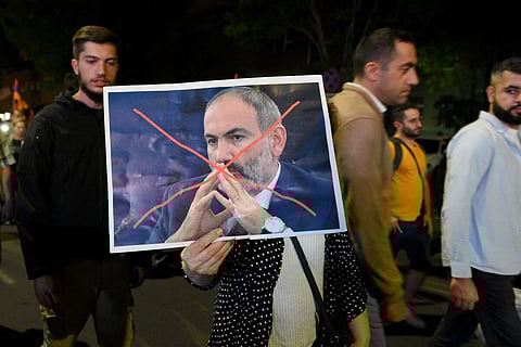 A protestor holds a crossed-out portrait of Armenia's PM Nikol Pashinyan during an anti-government rally in downtown Yerevan on September 2023, following Azerbaijani military operation. (Photo | AFP)
