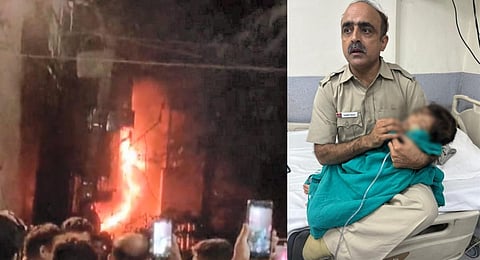 A police official holds a rescued baby at a hospital after a fire broke out in a building in Delhi's Mukherjee Nagar, on Sept 27, 2023. (PTI)