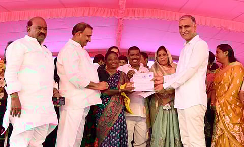 Finance Minister Harish Rao hands over ownership documents to the beneficiaries of double bedroom houses at Kollur near Hyderabad on Saturday. (Photo | Express)