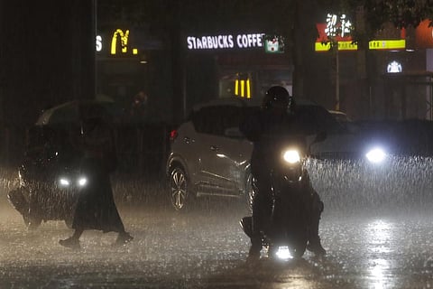 People walk and drive under heavy rain as the Typhoon Haikui approaches the country, in Taipei, Taiwan. (Photo | AP)