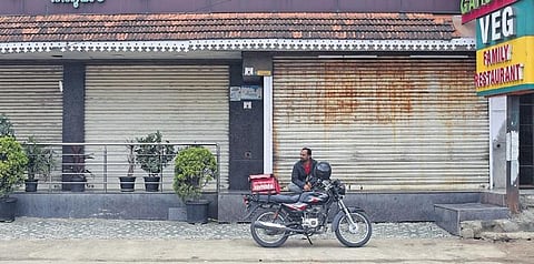 A food delivery executive waits for hotels to open to collect the order during the bandh on Friday