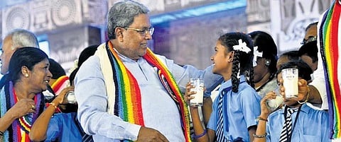 Chief Minister Siddaramaiah interacts with schoolchildren on the 10th anniversary of Ksheera Bhagya Yojana in Madhugiri, Tumakuru district, on Wednesday | Express