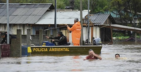 Police officers check a house as residents wade through a flooded street after floods caused by a cyclone in Passo Fundo, Rio Grande do Sul state, Brazil.(AP Images)
