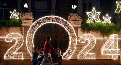 People take selfies against the 'Welcome 2024' display, at Walkeshwar, in Mumbai on Sunday, Dec. 31, 2023. (PTI)