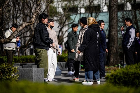 A group of men gather to smoke at a public smoking area on the side of a road in Seoul on March 13, 2023. (File Photo | AFP)