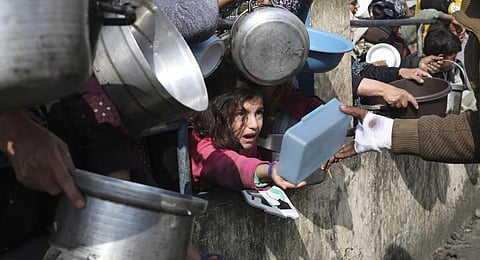 Palestinians line up for free food during the ongoing Israeli air and ground offensive on the Gaza Strip in Rafah. (Photo | AP)
