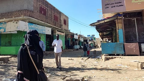 Sudanese civilians walk through a nearly empty road with many shops closed for security reasons in Gedaref city in eastern Sudan.