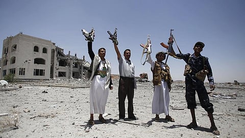 Houthi rebels hold up their weapons at the residence of a military commander of the Houthi militant group, in Sanaa, Yemen.