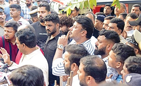 Actor Darshan gestures to the crowd outside the Subramanyanagar police station in Bengaluru on Friday. Actor Abhishek Ambareesh looks on | vinod kumar t