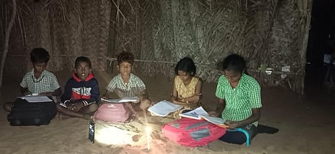 Children in Sintha Nagar study under the light of a mobile phone flashlight.