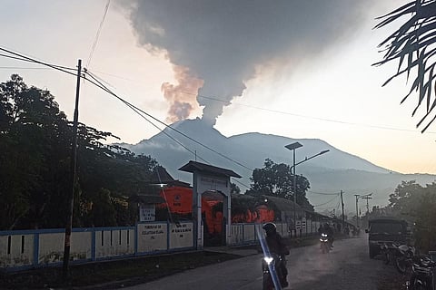 Motorists ride as mount Lewotobi Laki-Laki spews hot smoke in Flores Timur, Nusa Tenggara, Timur province on January 2, 2024. (Photo | AFP)
