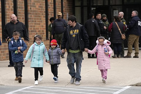 A man and children leave the McCreary Community Building after being reunited following a shooting at Perry High School. (Photo | AP)