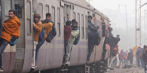 Passengers hang out from a train as it approaches a station during a cold and foggy winter morning, in New Delhi. (Photo | PTI)