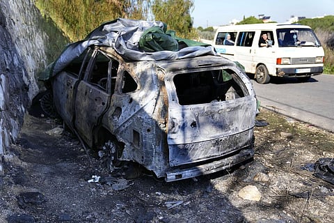 A minibus passes the attacked car that was used by the senior Hezbollah commander Wissam Tawil, who was killed on Monday, in Kherbet Selem village, Lebanon, Tuesday, Jan. 9, 2024. (Photo | AP)